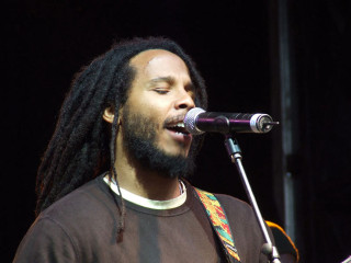 Man dreadlocks singing microphone stage - a guitar in front free wallpaper