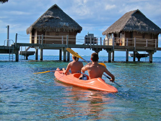 Kayak paddling towards pier thatched - hut free wallpaper