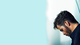 Bearded man black shirt leaning - against a wall free wallpaper