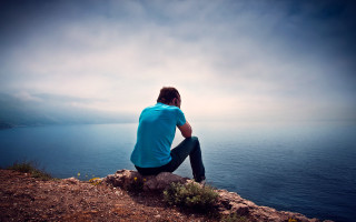 Man sitting rock ocean cloudy - daryush shokof free wallpaper