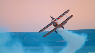 Biplane flying water person back - over a body of water free wallpaper