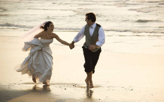 Bride groom walking beach holding 3 - the ocean in the background free wallpaper