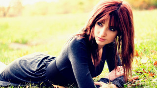 Woman laying grass wind hair - the ground in a field of grass free wallpaper