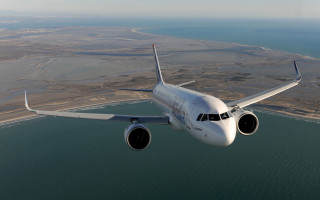 Jetliner over ocean beach town - aerial free wallpaper
