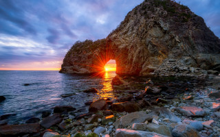 Large rock formation sunset water - a body of water below free wallpaper