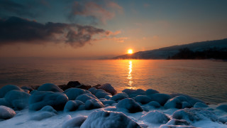 Sunset water snow rocks mountain - a sunset over a body of water free wallpaper