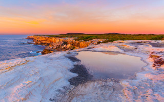 Sunset ocean cliff shore pastel - a large body of water free wallpaper