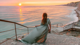 Woman ocean sunset railings mountains - looking free wallpaper