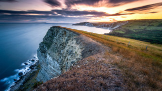 Cliff ocean sunset landscape planet 2 - a sunset in the background and a body of water free wallpaper