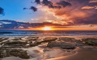 Sunset ocean rocks water cloudy 2 - a sun setting free wallpaper