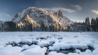 Snowy mountain range stream snow - the foreground and a forest in the background free wallpaper