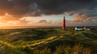 Red lighthouse green field ocean - a cloudy sky free wallpaper