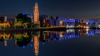 Large clock tower river night - side and a city in the background free wallpaper