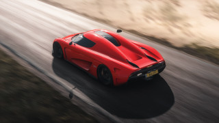 Red sports car driving forest 6 - a hill in the background free wallpaper