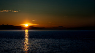 Sunset mountains water orange sky 2 - a sunset over a body of water free wallpaper
