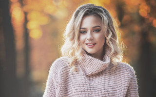 Blonde woman pink sweater smiling - a forest in the background free wallpaper