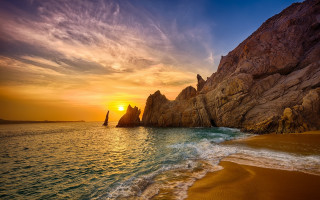 Beach rock formation sailboat sunset - a sailboat free wallpaper