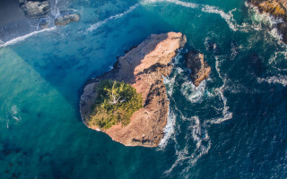 Aerial rock formation tree ocean - a body of water below free wallpaper