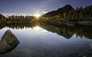 Lake rock sunshine forest mountains - a rock in the middle of it free wallpaper