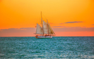 Sailboat sunset water reflection mountain - a red sky in the background free wallpaper for desktop