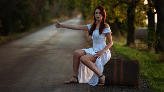 Woman sitting suitcase pointing outdoors - her free wallpaper