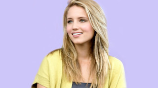 Blonde woman yellow cardigan smiling - against free wallpaper