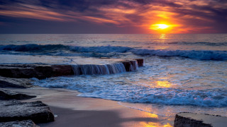 Sunset ocean waves rock wall - a small waterfall free wallpaper