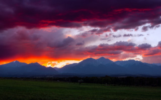 Mountain sunset clouds green field - a green field below free wallpaper