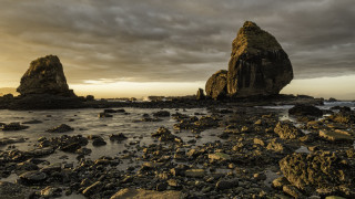 Rocky beach formation cloudy sky - a large rock formation in the middle of it free wallpaper