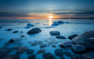 Sunset water rocks beach horizon - a sunset over a body of water free wallpaper