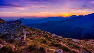 Mountain sunset rocky field cityscape - a grassy field below free wallpaper