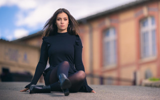 Woman black dress sitting outdoors - a building in the background free wallpaper