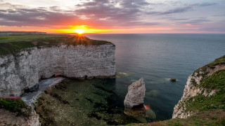 Sunset cliff rocks water boat - a body of water below free wallpaper