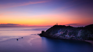 Sunset lighthouse boat water sky - a sunset over a body of water free wallpaper