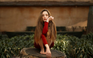 Woman longhair reddress sitting outdoors - her hand behind her head free wallpaper