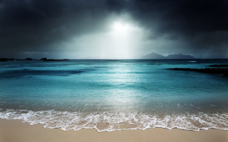 Beach waves sunbeam mountain stormy - a mountain in the distance free wallpaper