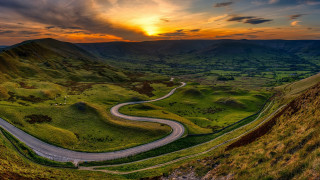 Winding road lush green valley - a lush green valley under a cloudy sky free wallpaper