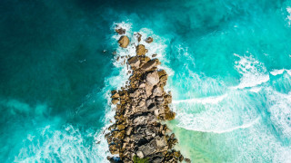Rocky outcropping ocean bubbles fish - a body of water below free wallpaper