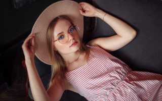 Woman hat glasses couch portrait - her arm behind her head free wallpaper