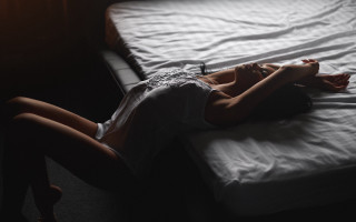 Woman laying bed dark room - a white sheet free wallpaper