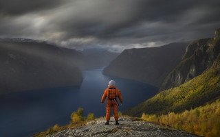 Man orange suit cliff lake - cloudy free wallpaper