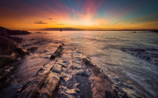 Sunset ocean boat rocky shore 2 - a boat in the distance free wallpaper