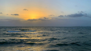 Sunset ocean waves boat city - a boat in the distance free wallpaper