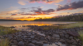 Sunset lake rocks grass forest - the foreground and a forest in the background free wallpaper