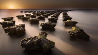 Sunset rocks water bridge cityscape - the sun setting behind them free wallpaper