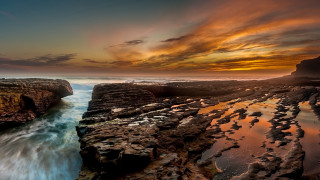 Sunset rocky beach water cliff 5 - a sunset over a rocky beach free wallpaper