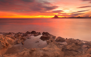 Sunset water rocks mountain city 2 - a sunset over a body of water free wallpaper