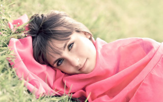 Girl smiling laying in grass - a young girl free wallpaper