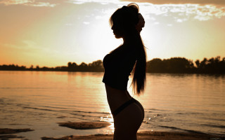Woman beach sunset ponytail backlighting - the sun setting behind her free wallpaper