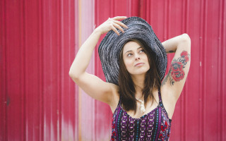 Woman hat red wall portrait - her arm behind her head free wallpaper